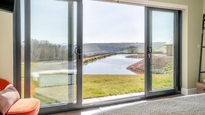 A room with a large sliding glass door leading to a scenic outdoor view of a river and fields. - 3 Bed in Merthyr Cynog (oc-g30312) (Brecon)