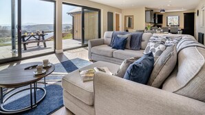 A spacious living room with a large sofa, a coffee table, and a dining area with a table and chairs. - 3 Bed in Merthyr Cynog (oc-g30312) (Brecon)