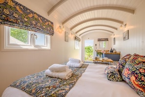 Ein Zimmer mit einem Bett, zwei Nachttischen, einem Fenster und einer Tür, die auf einen Balkon führt.