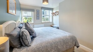 A bedroom with a large bed, two windows, a radiator, and a ceiling light fixture. - 1 Bed in Skipton (oc-w30426) (Skipton)