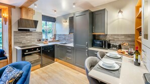 A modern kitchen with grey cabinets, a built-in oven, and a dining area with a table set for two. - 1 Bed in Skipton (oc-w30426) (Skipton)