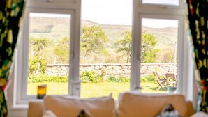 A room with a large window overlooking a stone wall and greenery. - 3 Bed in Hawes (oc-s30429) (Hawes)