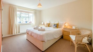 A bedroom with a large bed, a bedside table with a lamp, a wicker chair, and a window with curtains. - 3 Bed in Hawes (oc-s30429) (Hawes)