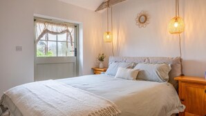 A bedroom with a bed, bedside tables, a window with curtains, and two hanging light fixtures. - 3 Bed in Whitwell (oc-d30478) (Godshill)