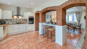 A modern kitchen with white cabinets, a brick archway, and a dining area with a table and chairs. - 6 Bed in Rudston (oc-s30441) (Rudston)