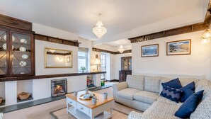 A living room with a fireplace, a sofa, a coffee table, and a chandelier. - 6 Bed in Rudston (oc-s30441) (Rudston)