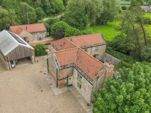 A stone building with a red-tiled roof, surrounded by greenery and a gravel driveway. - 1 Bed in Crakehall (oc-o30357) (Kirkbridge)