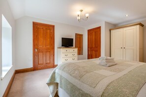 Ein Schlafzimmer mit einem Bett, einem Schminktisch, einem Fernseher und zwei Türen.