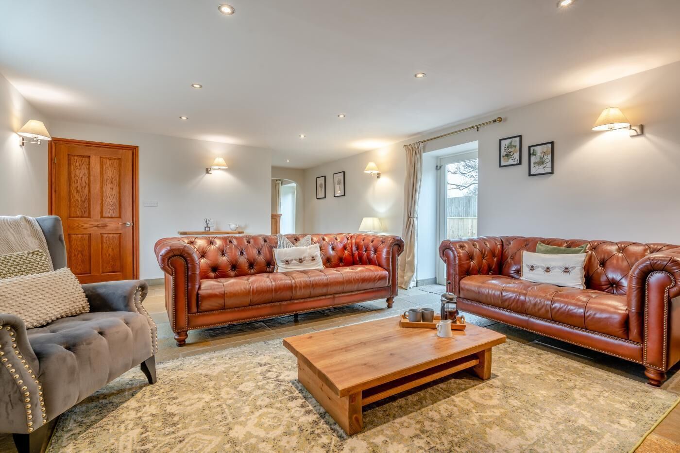 A living room with two leather sofas, a wooden coffee table, and a grey armchair.
