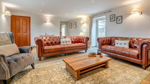 A living room with two leather sofas, a wooden coffee table, and a grey armchair. - 3 Bed in Crakehall (oc-m30356) (Kirkbridge)