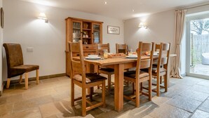 A dining area with a wooden table and chairs, a cabinet with glass doors, and a window with curtains. - 3 Bed in Crakehall (oc-m30356) (Kirkbridge)