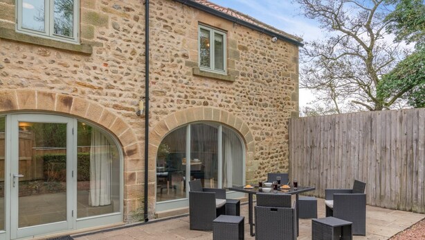 A stone building with a patio area featuring wicker furniture and a table with drinks. - 2 Bed in Crakehall (oc-m30355) (Kirkbridge)
