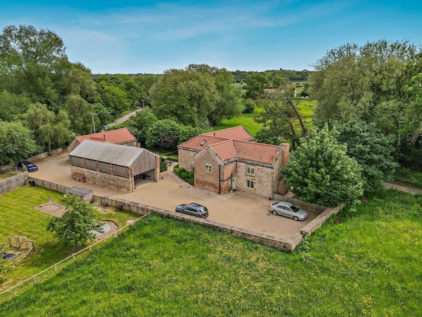 A rural property with a stone barn, a small house, and a paved driveway.