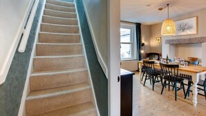Eine Treppe mit Teppichstufen führt zu einem Essbereich mit einem Holztisch und Stühlen.