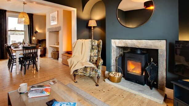 Ein gemütliches Wohnzimmer mit Kamin, einem Essbereich mit Tisch und Stühlen sowie einem großen Spiegel an der Wand.