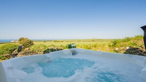 Un bain à remous offrant une vue dégagée sur l’océan et un paysage verdoyant.