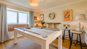 Une table de billard dans une pièce avec une fenêtre, une lampe et un tableau encadré au mur.