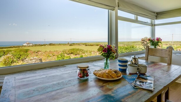 Une table à manger dressée pour le petit-déjeuner, avec vue sur la mer.