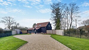 Een huis met een grindpad, een omheinde tuin en een houten omheining.