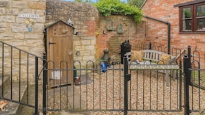A stone building with a wooden gate, a bench, and a sign warning about a penalty for not shutting the gate. - 1 Bed in Queen Camel (oc-c30506) (Queen Camel)