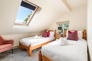A bedroom with two beds, a skylight, a radiator, and a chair. - 4 Bed in St. Brides (oc-h30490) (Saint Brides)