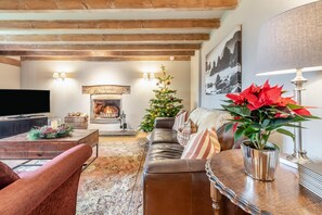 A cozy living room with a fireplace, a television, and a Christmas tree. - 4 Bed in St. Brides (oc-h30490) (Saint Brides)