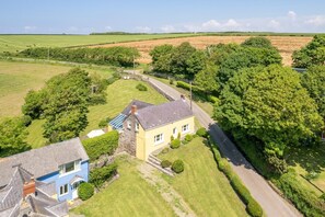 A rural house with a paved driveway, surrounded by lush greenery and fields. - 4 Bed in St. Brides (oc-h30490) (Saint Brides)