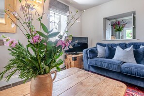 A living room with a blue sofa, a wooden coffee table, and a TV on a wooden stand.