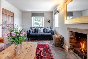 A cozy living room with a fireplace, a dark blue sofa, a wooden coffee table, and a patterned rug.