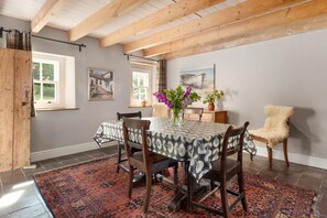 A dining area with a round table, chairs, a rug, and artwork on the walls. - 2 Bed in St. Brides (oc-k30489) (Saint Brides)