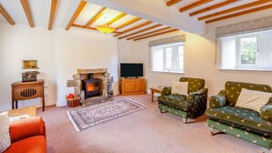 A cozy living room with a fireplace, wooden beams, a television, and patterned furniture. - 4 Bed in Mallerstang (oc-s22487) (Mallerstang)
