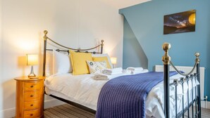 Quarto bem arrumado com cama, abajures, mesa de cabeceira de madeira e um quadro na parede.
