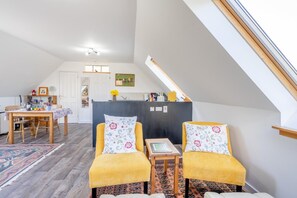 Ett rum i loftstil med en matplats, ett litet bord med stolar och utsikt mot himlen genom ett takfönster.