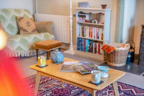 A cozy living room with a wooden coffee table, a bookshelf, and a patterned rug.