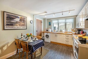 A compact kitchen with a dining area, a washing machine, and a large window.