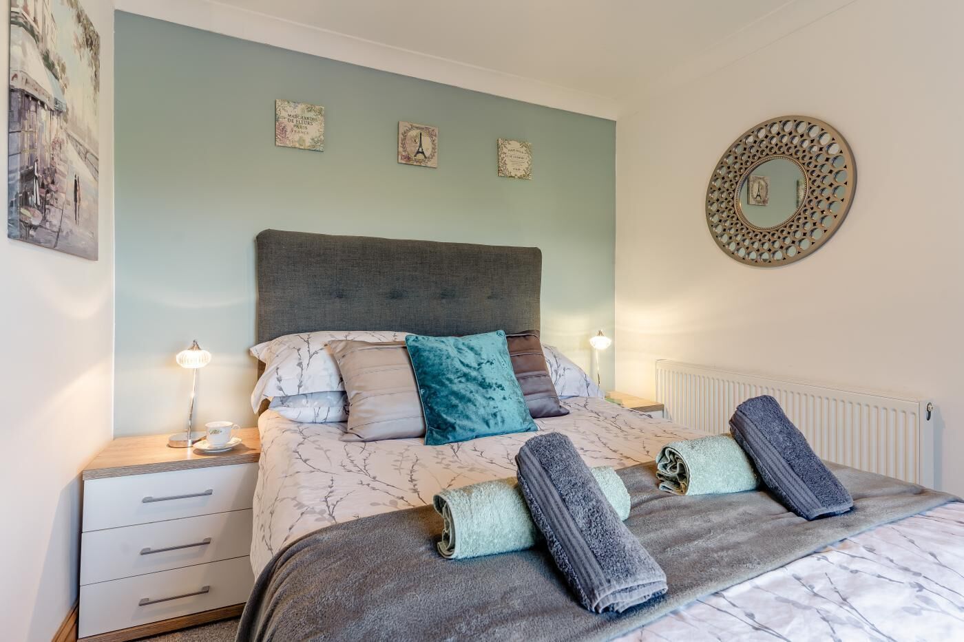 Un dormitorio con cama, mesitas de noche y adornos en la pared.