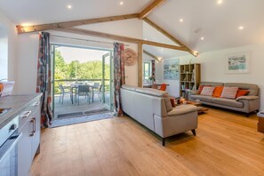 A modern living room with a sofa, a dining area with chairs, and a kitchen area. - 3 Bed in Winnards Perch (oc-m30557) (Winnard's Perch)