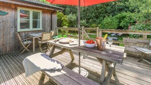 A wooden deck with a table, chairs, and a red umbrella. - 3 Bed in Winnards Perch (oc-m30557) (Winnard's Perch)