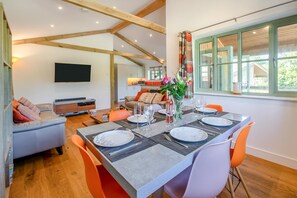 A dining area with a table set for six, a sofa, and a TV in the background.