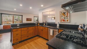 A modern kitchen with wooden cabinets, a black countertop, and a gas stove. - Waterfront Cabin with expansive deck near Saratoga & Lake George (Corinth)