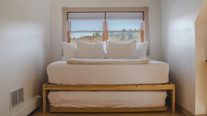 A bed with a view of trees through a window. - Waterfront Cabin with expansive deck near Saratoga & Lake George (Corinth)
