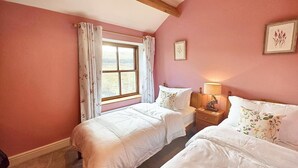 A bedroom with two beds, a window with curtains, a bedside lamp, and framed artwork on the wall. - 3 Bed in Garsdale (oc-l30314) (High Abbotside)