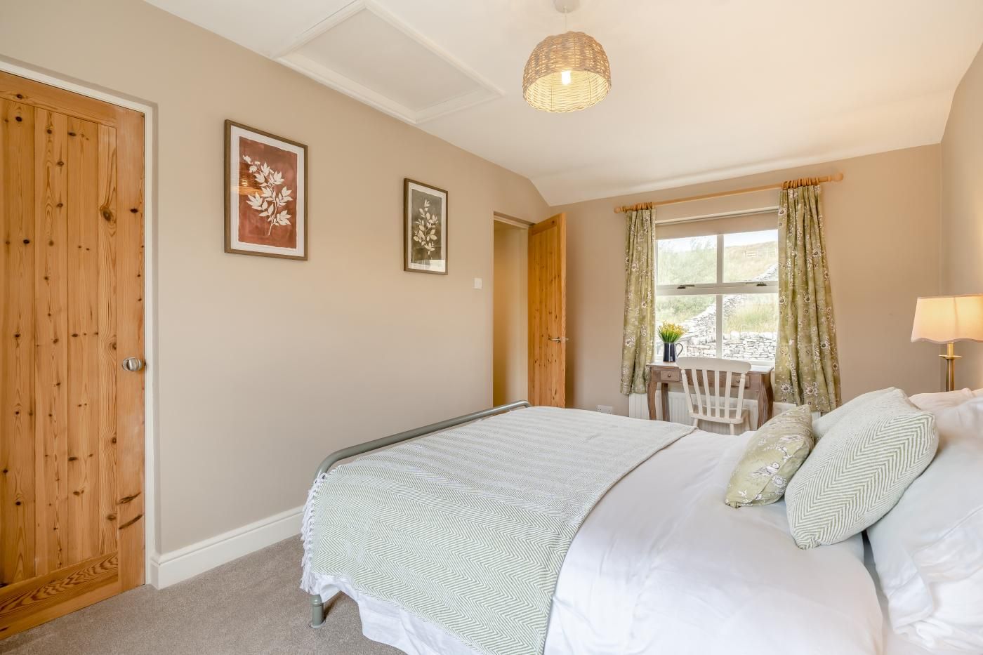 A bedroom with a bed, a desk, a chair, and a window with curtains.
