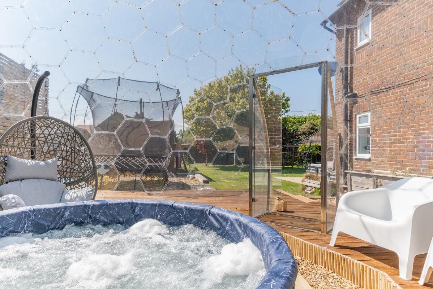 A hot tub, a wicker chair, and a glass enclosure with a hexagonal pattern.