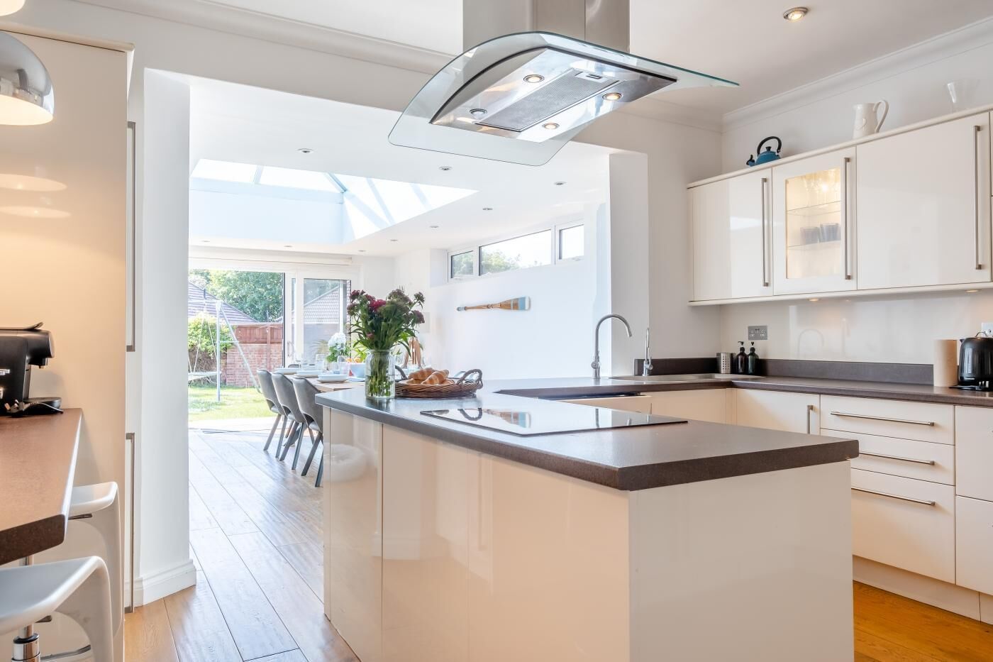 A modern kitchen with a central island, white cabinetry, and a large window providing natural light.
