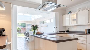 Una cocina moderna con una isla central, armarios blancos y un amplio ventanal que proporciona luz natural.