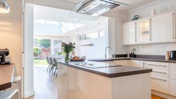 A modern kitchen with a central island, white cabinetry, and a large window providing natural light.
