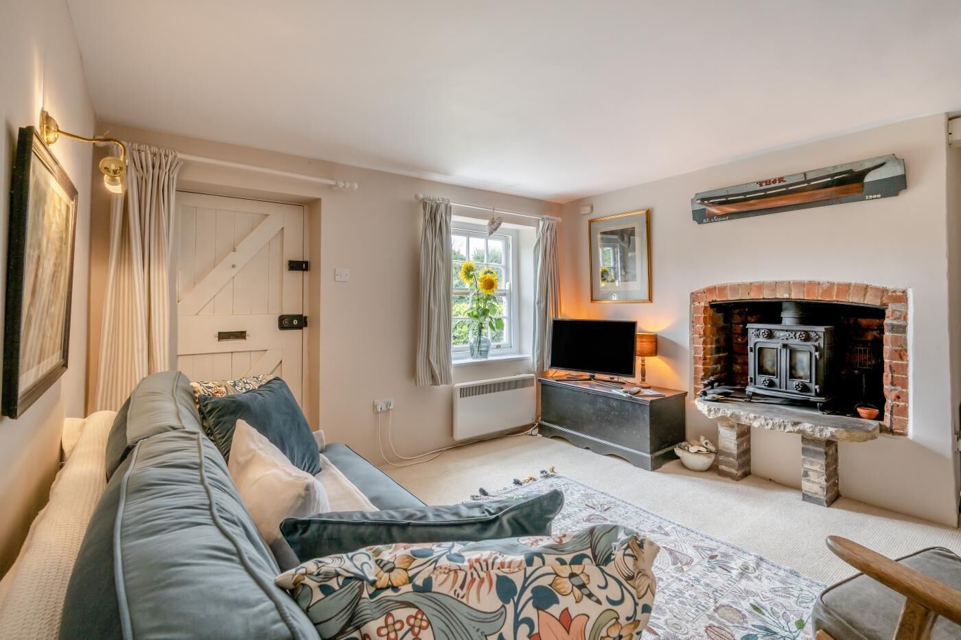 A cozy living room with a sofa, a television, a fireplace, and a window with curtains.