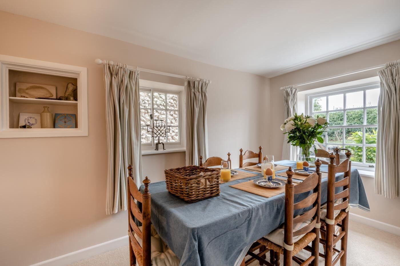 A dining room with a table set for breakfast, including plates, glasses, and a basket.