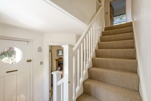 A staircase with beige carpeted steps and white railings, leading to an upper floor.
